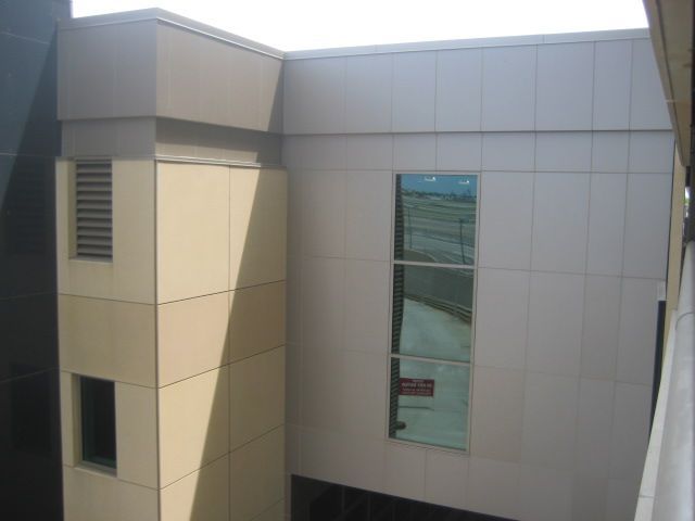 Beige and white building exterior with a window and air vent.