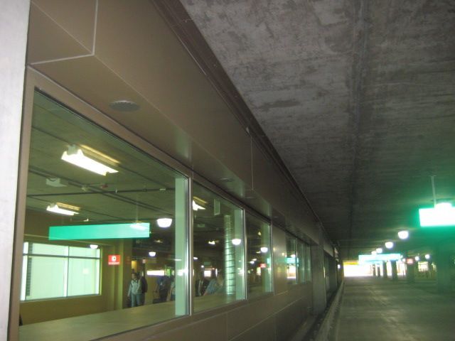 Long view inside a public transit station, with windows, concrete ceiling, and distant signage.