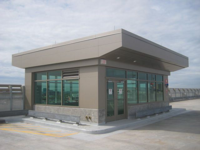 A tan, square security booth on a rooftop with glass windows and a flat roof.