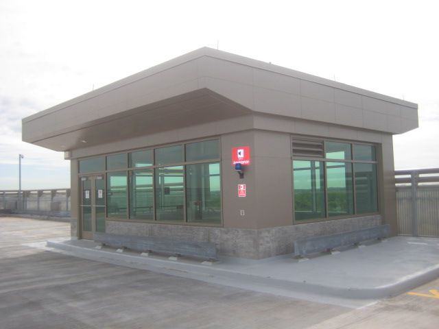 Beige toll booth with tinted windows on a concrete surface, likely atop a parking garage.