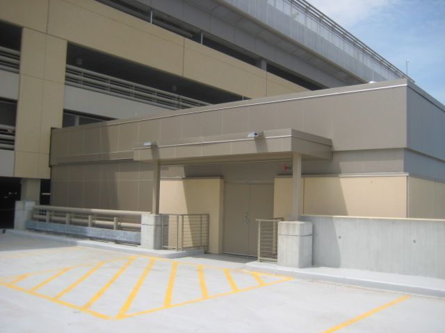 Exterior view of a building with a covered entrance, parking space, and a barrier gate.
