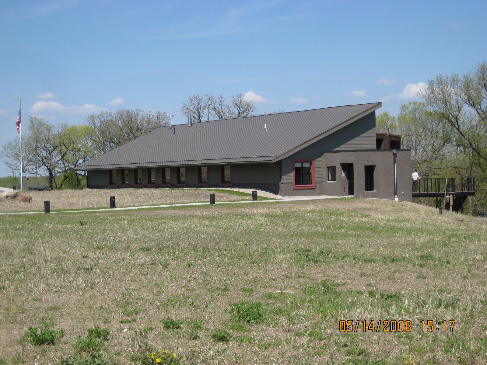 Building with sloped roof on a grassy hill, possibly a nature center or park building.