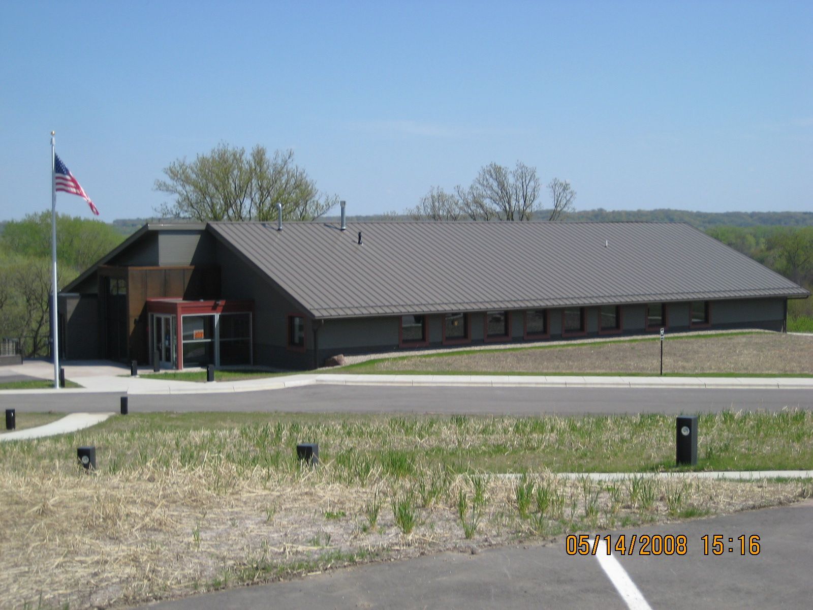 A one-story building with a gray roof and an American flag.