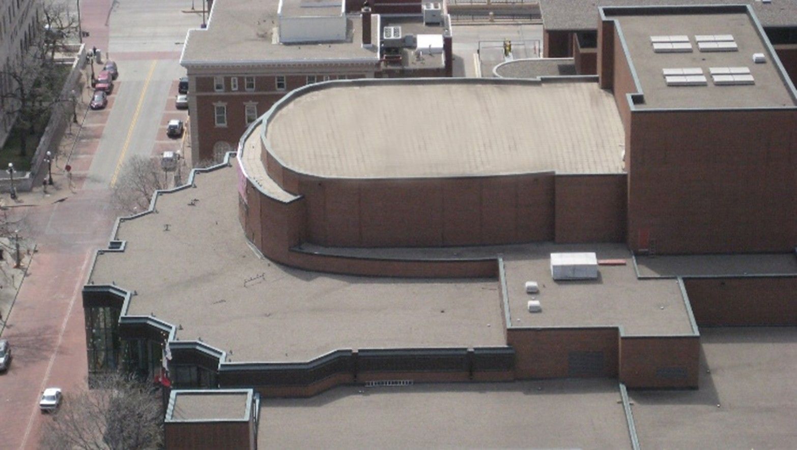 Aerial view of a large brick building with a curved roof and surrounding rooftop structures.