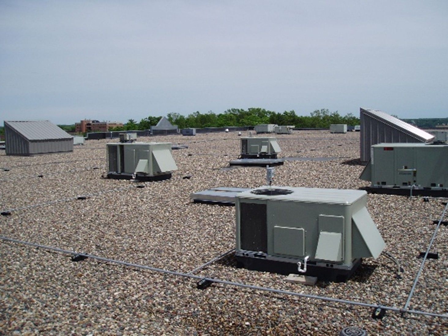The image depicts a commercial flat roof featuring a gravel-surfaced Built-Up Roofing (BUR) system