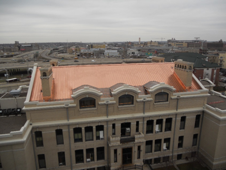 Roofer using air or pneumatic nail gun and installing on new roof metal sheet.