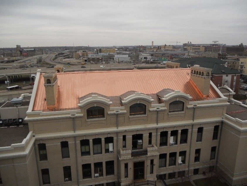 Rooftop view of a beige building with an orange roof overlooking a city skyline