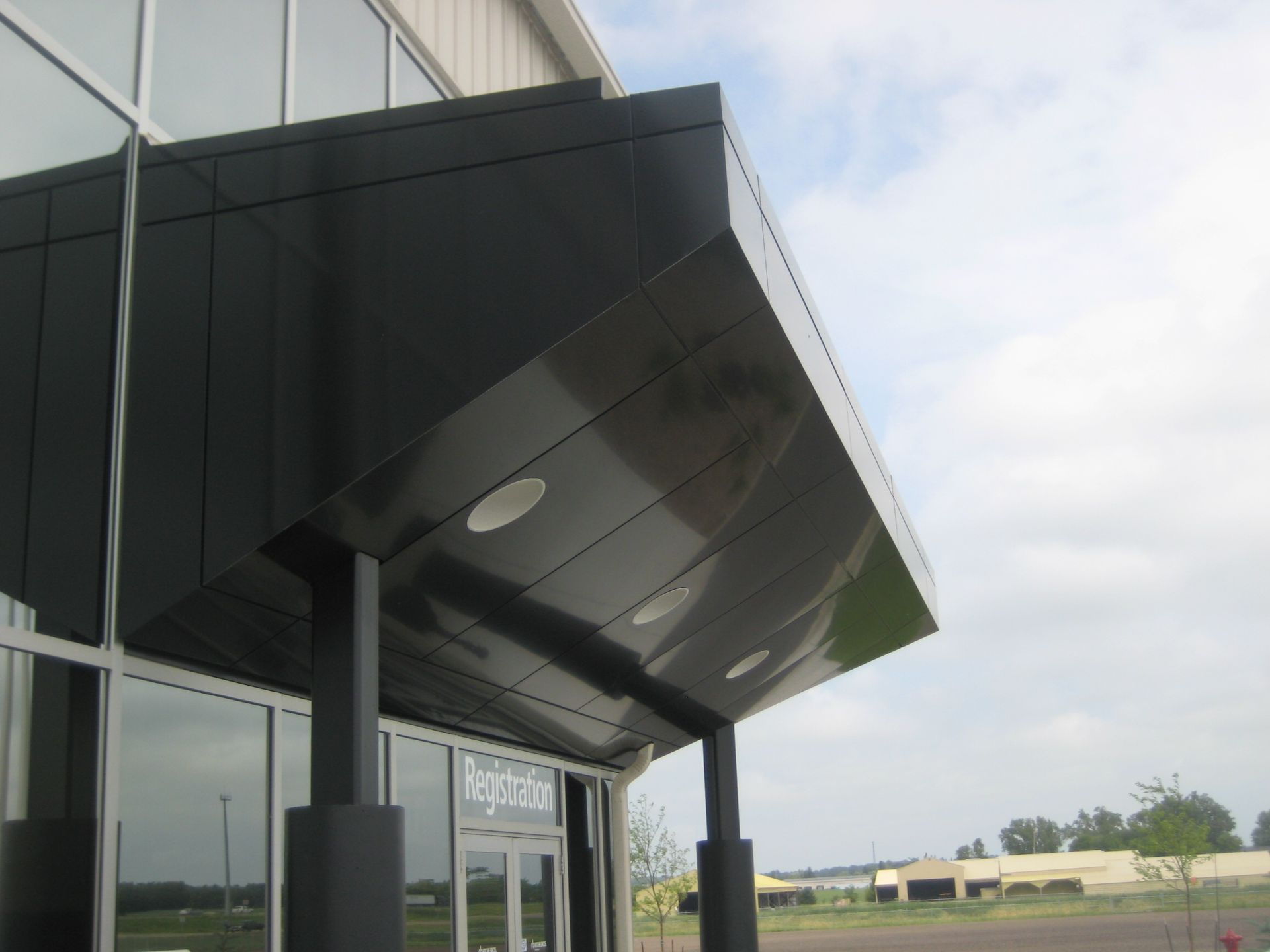 Black overhang above a building's entrance. Light-colored glass wall and door are visible.