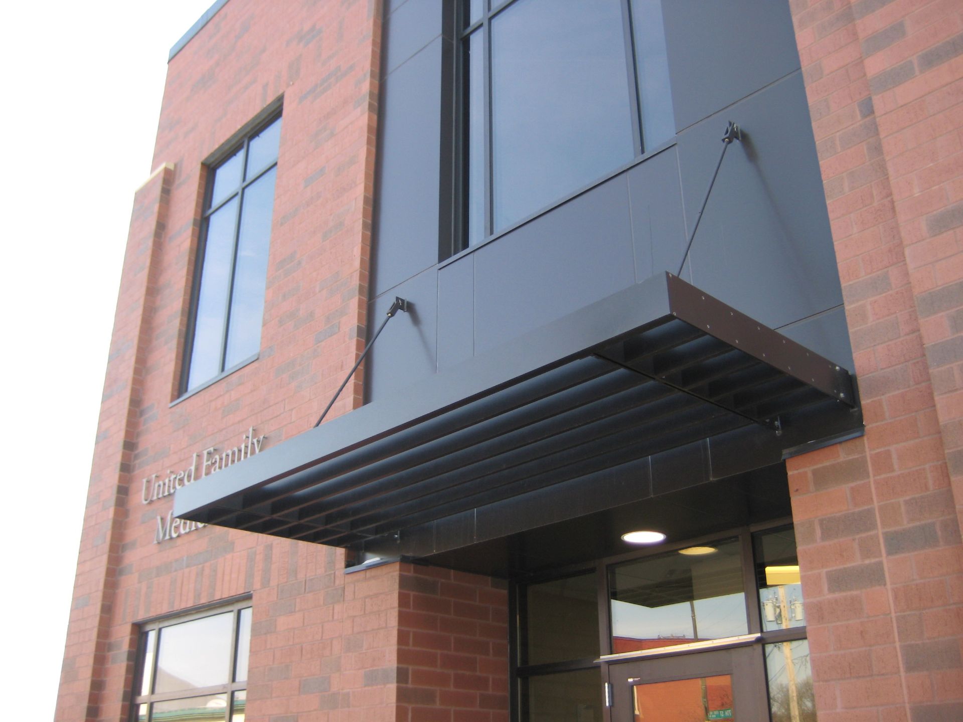 Building entrance with a black awning and red brick facade.