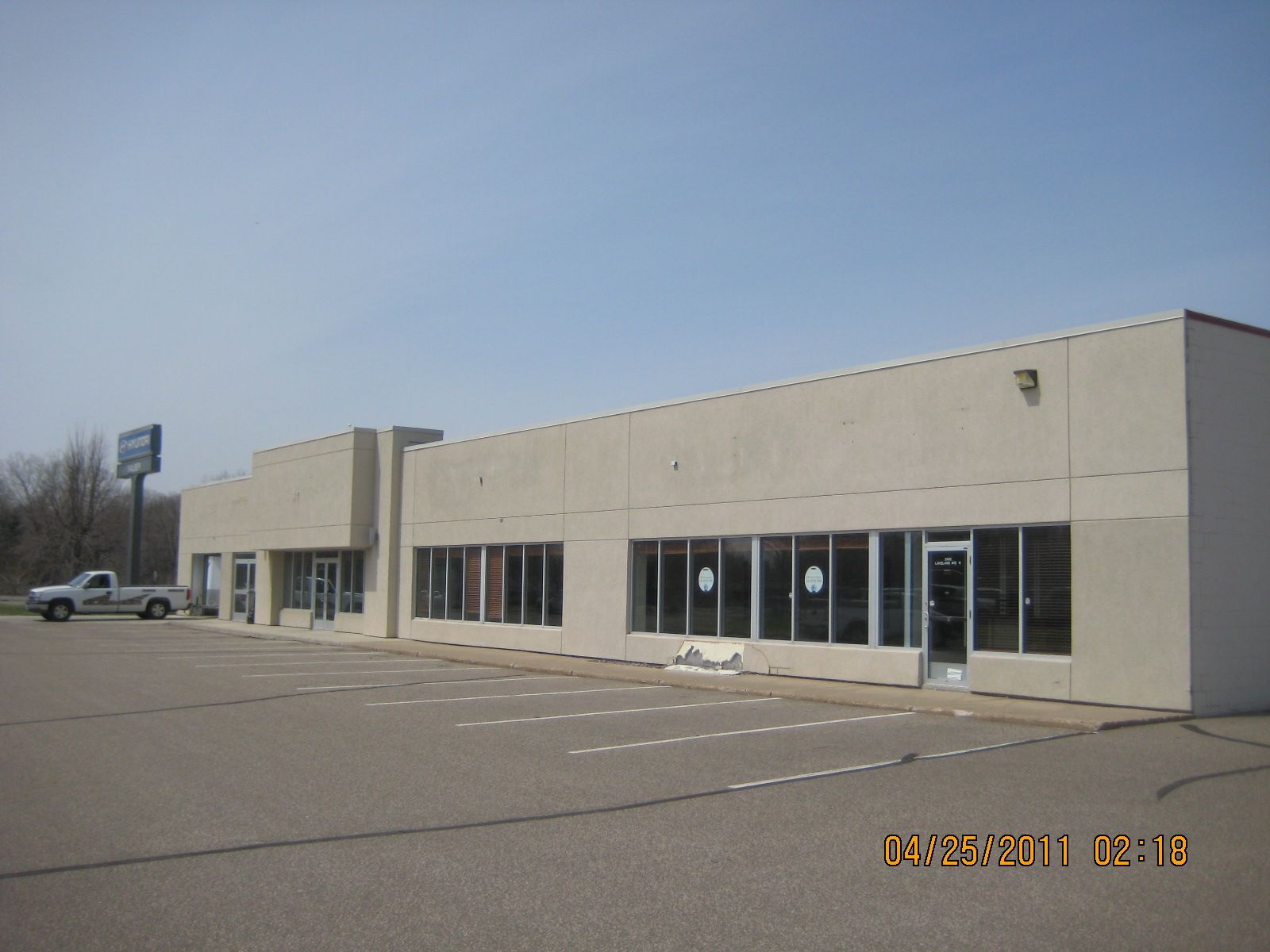 Exterior view of a one-story commercial building with multiple glass windows and a parking lot.