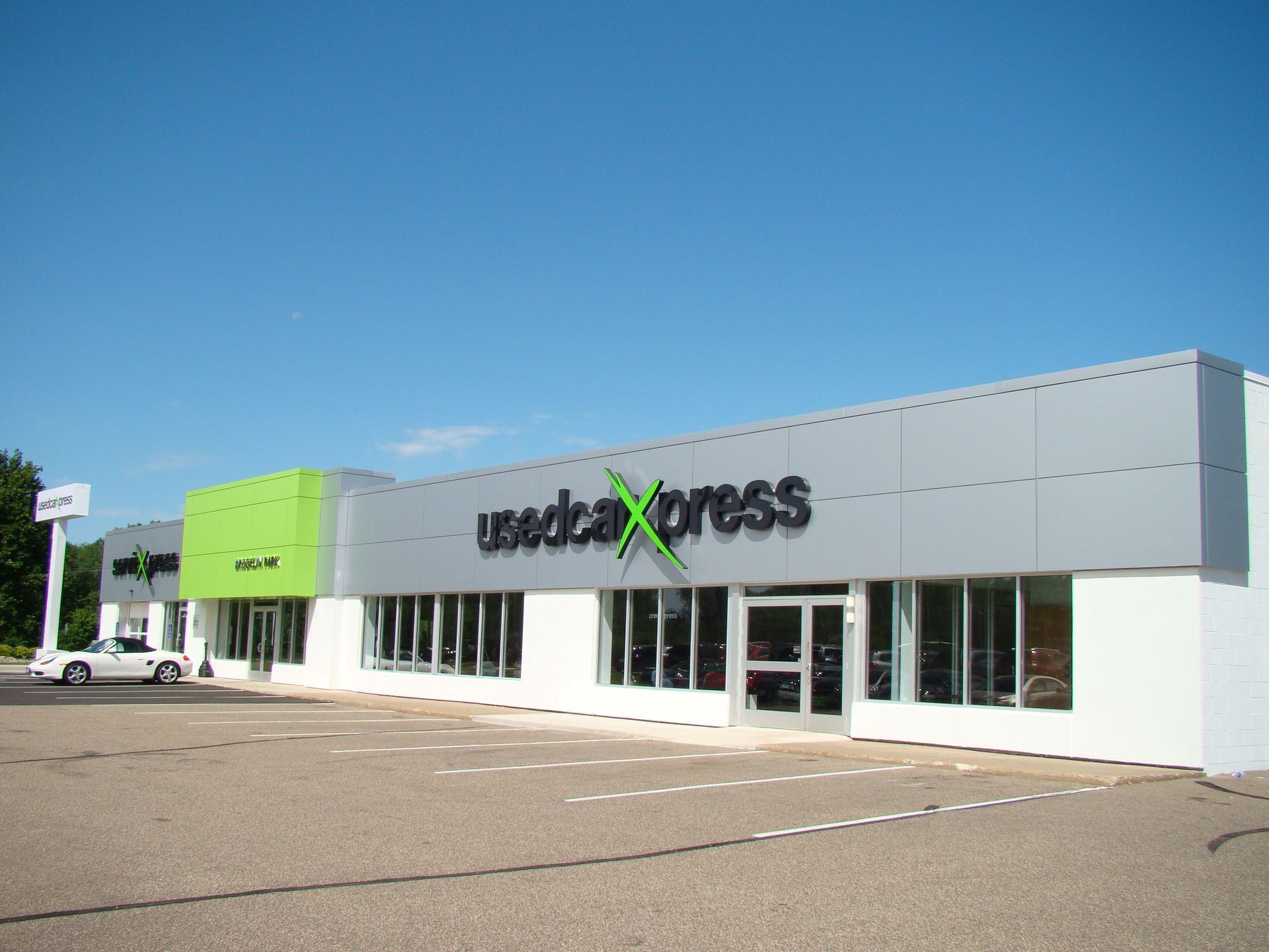 Used Car Express storefront with green and grey facade under a blue sky.