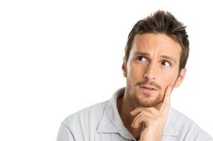 A man with a beard is thinking with his hand on his chin.