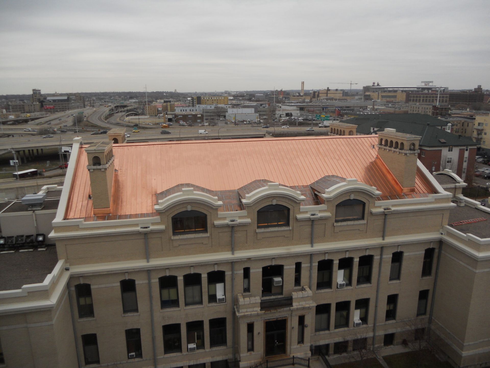 Top View - Minneapolis, MN - Berwald Roofing Overhead view of a building with a copper roof in an urban setting under a cloudy sky.