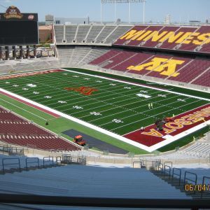 Football stadium, field with maroon and gold accents. Empty stands. 