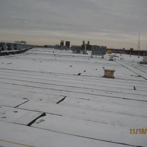 Flat roof with dark lines and scattered objects, gray sky overhead.