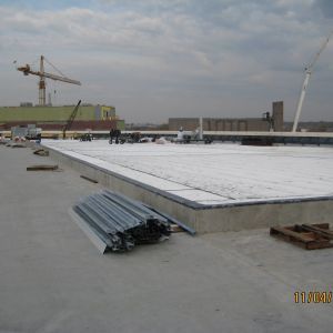 Rooftop construction site with crane and workers, materials on the roof.