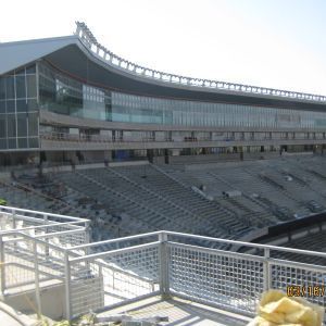 Stadium under construction with seating and a glass-walled structure on top.