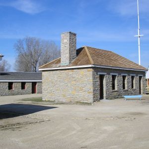 Stone buildings with brown roofs under a blue sky. One has a chimney.