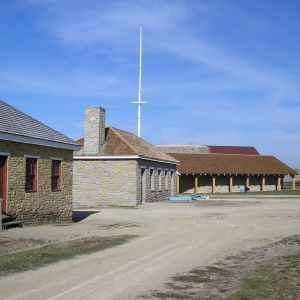 Buildings of a fort under a blue sky, with a long covered walkway.