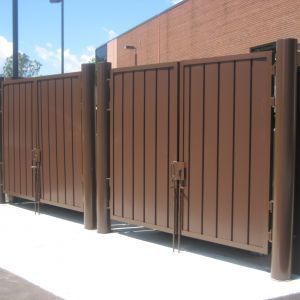 Brown metal dumpster enclosure with two gated doors.