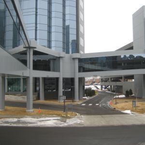 Exterior view of a modern building with skywalks over a driveway. Gray and glass architecture.