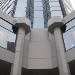 Exterior view of a modern building with gray pillars and large glass windows.