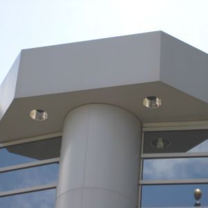 Modern building exterior with white pillars, windows, and hexagonal roof.