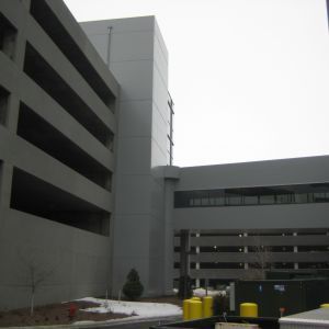 Gray concrete parking structure and connecting building on a cloudy day.