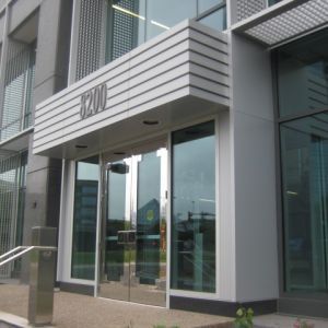 Entrance to a modern building with glass doors and a canopy displaying the number 8200.