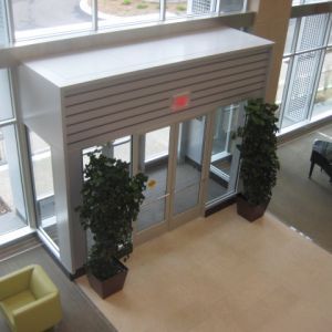 Glass doors with a canopy entrance, two potted plants, and an interior lobby.