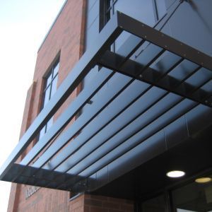 Black metal canopy over building entrance with brick facade.