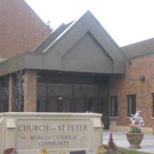 Church of St. Peter, Roman Catholic Community sign in front of a brick building with a covered entrance.