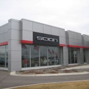 Scion dealership with gray and red facade, large windows, and the Scion logo.