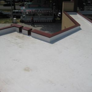 Flat white roof with red trim and a person walking.