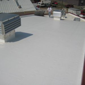 White commercial roof with vents; person standing.