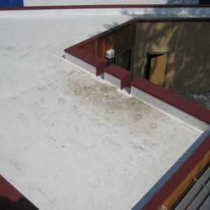 White flat roof with red trim, stains, and a doorway.