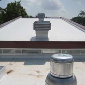 White roof with brown trim and metal vents, under a partly cloudy sky.