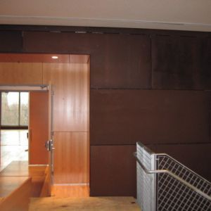 Brown paneled wall with a doorway and a metal handrail.
