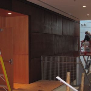 Door and dark panel wall with construction worker on lift.