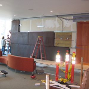 Interior construction site with workers, orange couch, and road construction pylons.