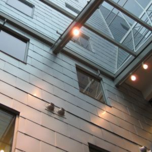 Exterior of modern building with silver paneling, windows, and glass roof.