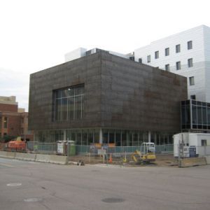 Modern building under construction with weathered steel exterior and large windows.