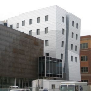 Modern building with reflective silver facade and small rectangular windows.