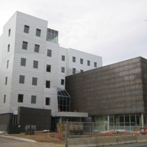 Modern, multi-story building with white and dark gray exterior, under construction.