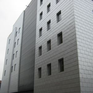 Gray, multi-story building with small, rectangular windows.