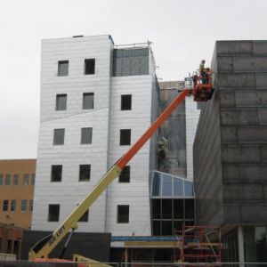 Construction workers on lift applying cladding to a modern building.