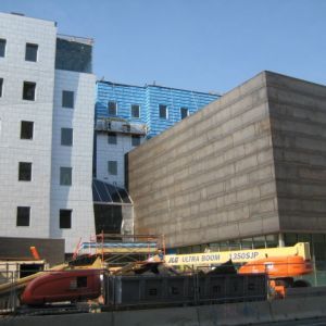 Buildings under construction with an orange lift, train, and blue sky.