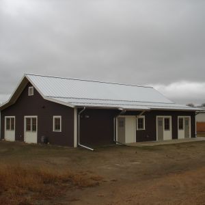 Brown building with white roof, doors, and trim on a cloudy day.