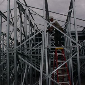 Construction worker on ladder attaching steel framing of a building.