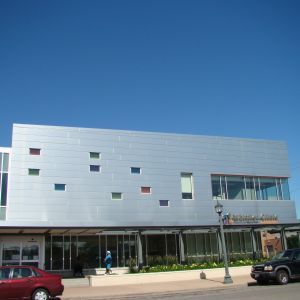 Modern building with silver facade, colorful square windows, and a clear blue sky.